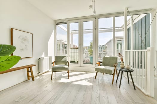 A serene and stylish indoor space featuring two elegant chairs, framed art, and abundant natural light streaming through large windows. Minimalist design enhances tranquility.