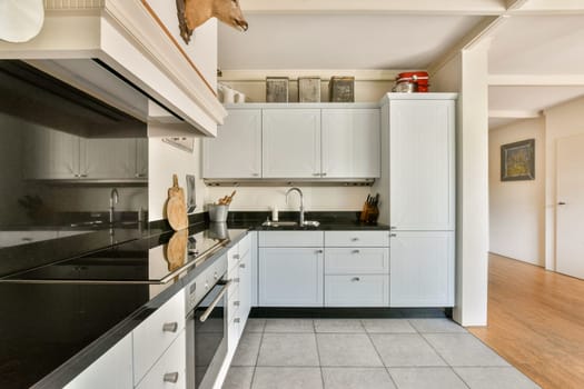 A sleek and stylish modern kitchen featuring white cabinetry, black countertops, and an open design that enhances the space. Perfect for culinary enthusiasts.