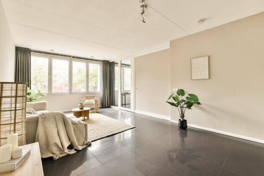 A tranquil modern living room featuring large windows, neutral colors, and minimalistic decor, ideal for relaxation and comfort with natural light flooding in.