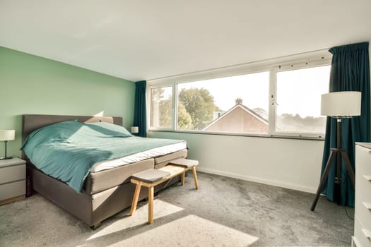 A serene and stylish bedroom showcasing a comfortable bed, soft textiles, and large windows inviting natural light, creating a calming atmosphere.