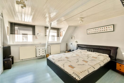 A bright and modern bedroom featuring a bed with patterned bedding, ample natural light, and minimalistic decor elements for a serene atmosphere.