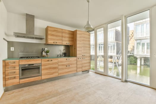 A contemporary kitchen featuring sleek wooden cabinets, stainless steel appliances, and large windows that flood the space with natural light. Ideal for modern living.