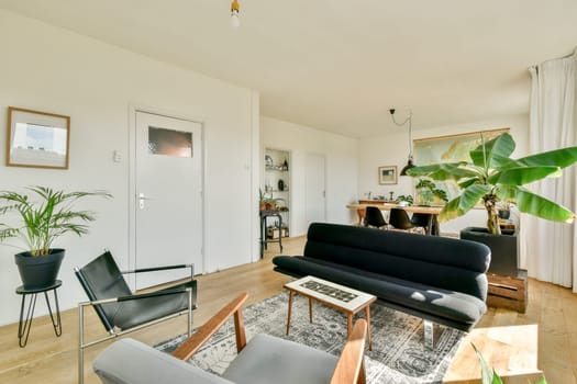 A contemporary living room featuring a stylish sofa, wooden furniture, and abundant plants, creating a fresh and inviting atmosphere.
