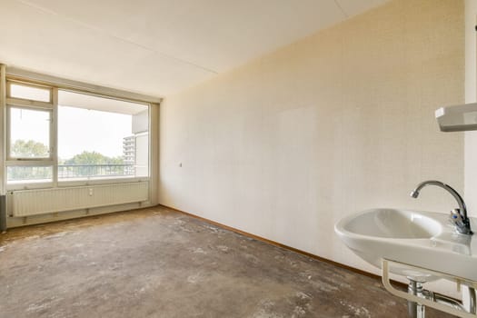 An empty room featuring large windows that allow natural light to flood in. The interior displays minimal decor and a simple design with basic amenities.
