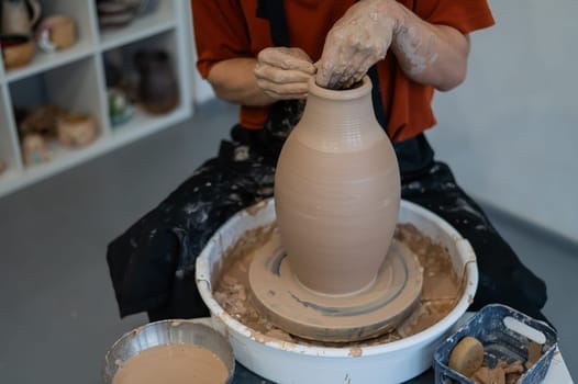 Close-up of a potter's hands making a ceramic vase on a potter's wheel