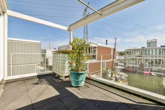 A stylish rooftop terrace featuring potted plants and a cityscape in the background. The scene captures urban living with a touch of greenery under a clear blue sky.