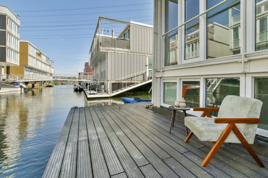 A stylish modern home with a wooden deck overlooking a calm canal, showcasing architectural elegance and serene water views.