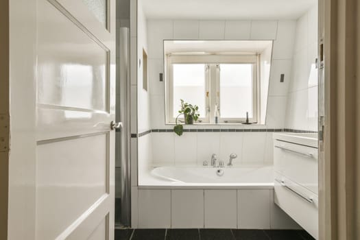 A stylish bathroom featuring a bathtub, sleek white tiles, and large windows allowing natural light to brighten the space. Perfect for relaxation and comfort.
