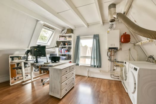 A well-organized home office featuring a desk, computer setup, and laundry area, illuminated by natural light through a large window.