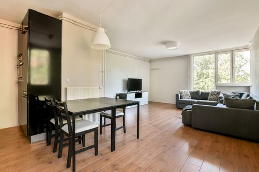 A stylish and contemporary living room featuring a chic dining area, cozy seating, and large windows allowing natural light to flood in.