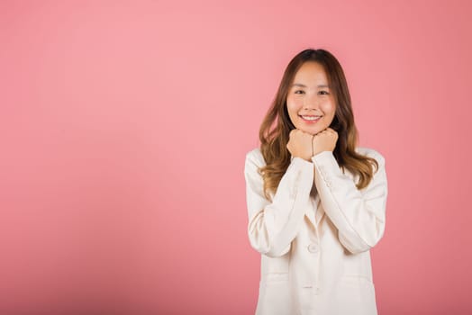 Asian happy portrait beautiful young woman standing smiling surprised excited her keeps hands pressed together under the chin studio shot on pink background with copy space for text
