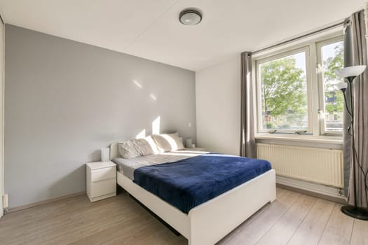 A stylish modern bedroom featuring a neatly made bed, large windows that allow natural light, and minimalistic decor creating a serene atmosphere.