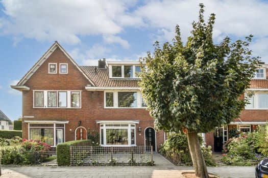 A picturesque residential building featuring a vibrant garden and surrounding greenery, creating a serene atmosphere in a suburban neighborhood.