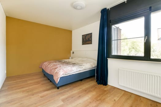 A sleek modern bedroom featuring a cozy bed, large window, and a combination of warm and cool tones. Natural light fills the space, creating an inviting atmosphere.