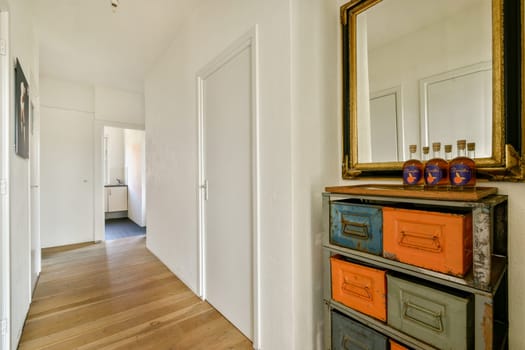 A contemporary hallway featuring a mirrored cabinet with vibrant drawers and a tastefully arranged decor, showcasing a blend of modern and vintage aesthetics.