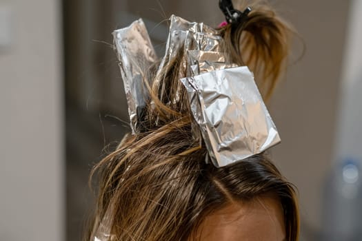 Hair coloring process is underway with foils in place for highlights, showcasing a creative transformation in progress.