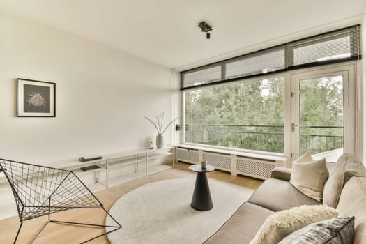 A contemporary living room featuring sleek furniture, large windows allowing natural light, and a minimalistic design. Ideal for cozy gatherings or relaxation.