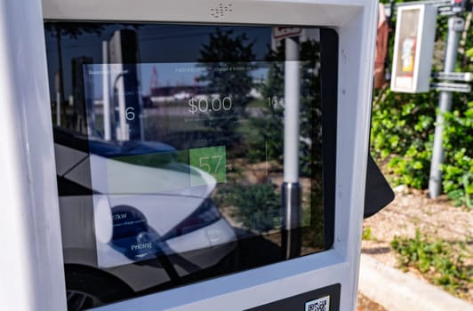 Austin, TX - 11 April 2025: Electrify America EV charger screen reflecting white car using free charging promotion for Hyundai