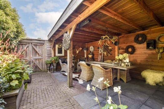 An inviting outdoor dining space featuring wooden beams, comfortable seating, and lush greenery, perfect for gatherings or relaxation.