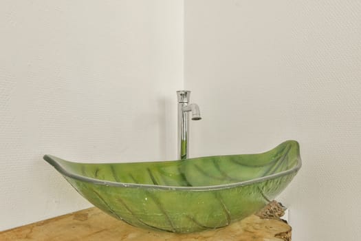 A stunning green sink shaped like a leaf, contrasting beautifully with its modern chrome faucet. Ideal for contemporary bathrooms or kitchens.