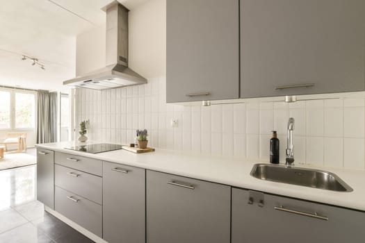 A sleek and stylish kitchen featuring gray cabinets, modern fixtures, and a clean countertop. Natural light enhances the inviting atmosphere for cooking and dining.