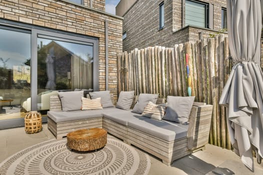 A modern patio featuring a comfortable lounge set surrounded by natural elements and wooden fencing, perfect for relaxation and outdoor gatherings.