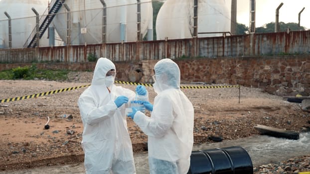 Ecologist sampling water from the river with test tube, Scientist or Biologist in a protective suit and protect mask collects sample of waste water from industrial for analyze, problem environment