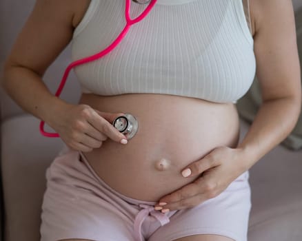 A pregnant woman listens to her baby's pulse using a phonendoscope