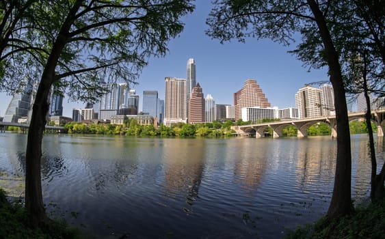 Fisheye lens view of Austin skyline including Congress bridge over the calm waters of Colorado river in Texas