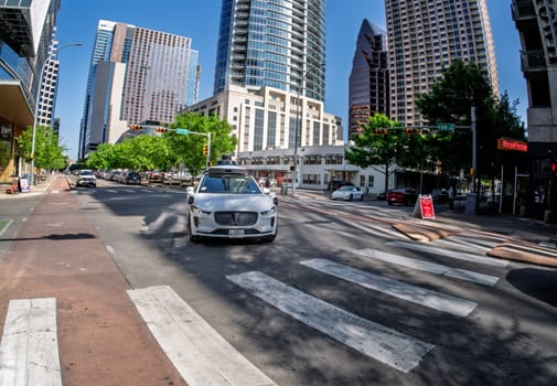 Austin, TX - 10 April 2025: Fisheye lens view of a Waymo Jaguar autonomous taxi turning at junction in downtown Austin, Texas