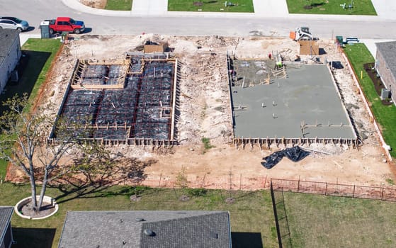 Overhead view of two construction sites, one with a concrete slab and the other a framed foundation ready for concrete