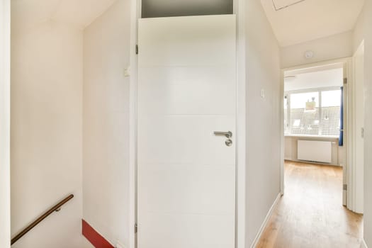 A clean, modern interior hallway featuring a white door and light wooden flooring, creating a bright and inviting atmosphere in the living space.