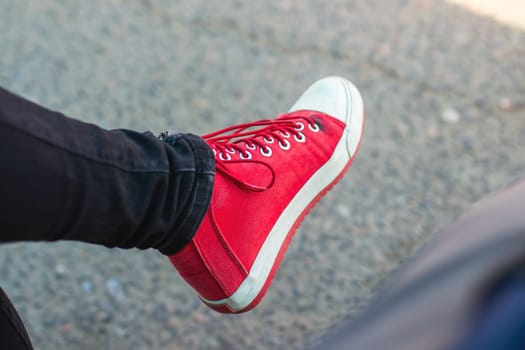This image features a closeup view of a person s foot that is wearing stylish red sneakers, showcasing vibrant colors and fashionable design