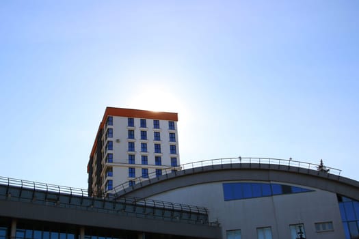 While gazing upwards, I admire a remarkably tall building, set against the backdrop of a vivid blue sky filled with soft, white clouds, creating a beautiful urban landscape