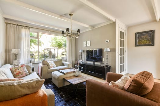 This inviting living room features a blend of modern and traditional furnishings, glowing natural light, and a serene outdoor view, creating a relaxing atmosphere.
