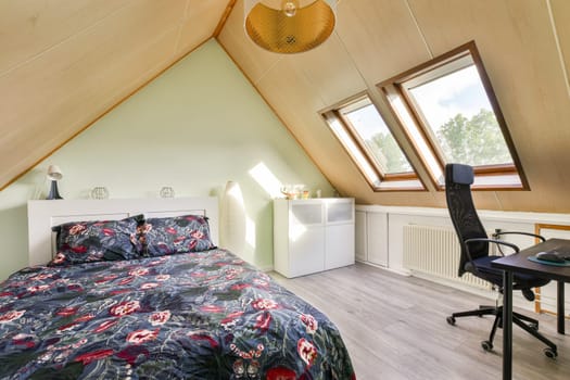 A well-lit modern bedroom featuring a cozy bed with floral bedding, a workspace, and large skylights that add natural light to the room.