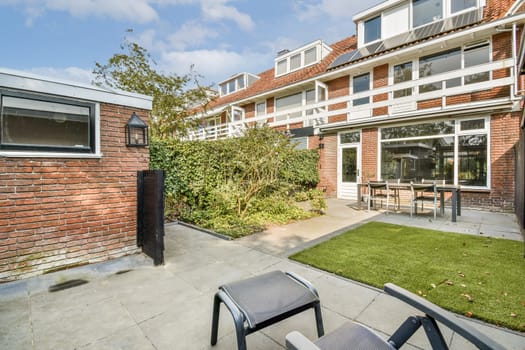 A contemporary backyard featuring well-maintained greenery, brick walls, and outdoor furniture, providing a serene space for relaxation and gatherings.