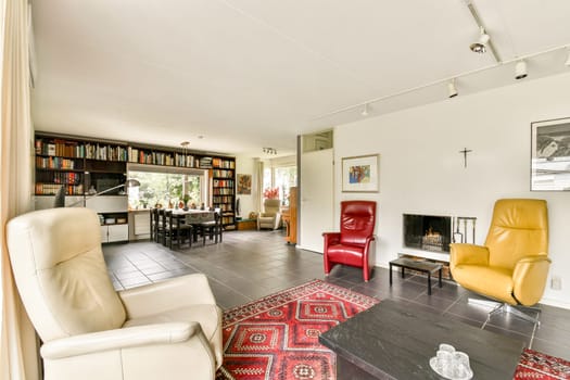 A spacious living room featuring elegant furniture, bookshelves, and vibrant decor, creating a warm and inviting atmosphere for relaxation.