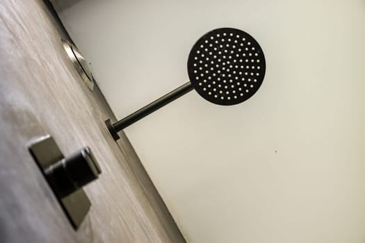 A sleek, modern shower head mounted in a minimalist bathroom setting features a unique design with a clean finish, emphasizing contemporary aesthetics.