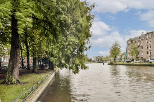 A beautiful view of a tranquil canal surrounded by vibrant greenery and charming architecture, perfect for a relaxing stroll or picturesque photography.