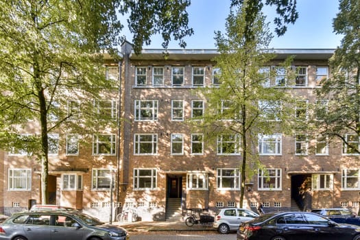 A contemporary urban apartment building surrounded by lush trees, featuring large windows and a welcoming facade in a vibrant neighborhood.