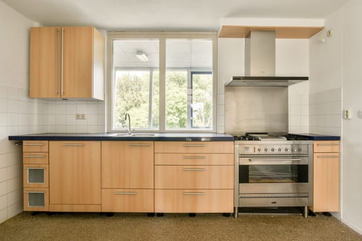 Bright and spacious kitchen featuring wooden cabinetry, contemporary appliances, and a large window that enhances natural lighting.