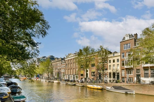 Charming view of a canal surrounded by beautiful buildings and lush trees, capturing the essence of Amsterdam's architecture and vibrant atmosphere.
