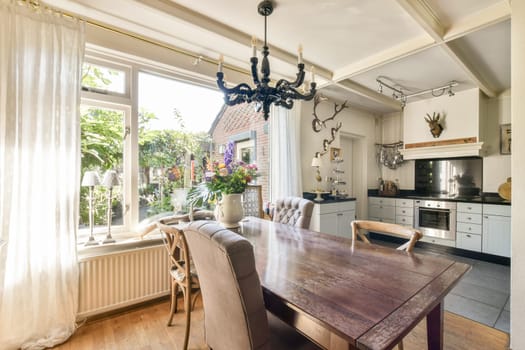 A sunlit dining area featuring a wooden table, elegant chairs, and large windows bringing in natural light, enhancing the homely ambiance.