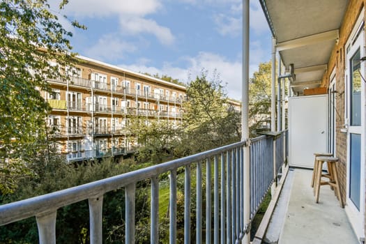 A stylish modern balcony featuring a clear view of surrounding greenery and adjacent buildings. Ideal for relaxation and enjoying fresh air.