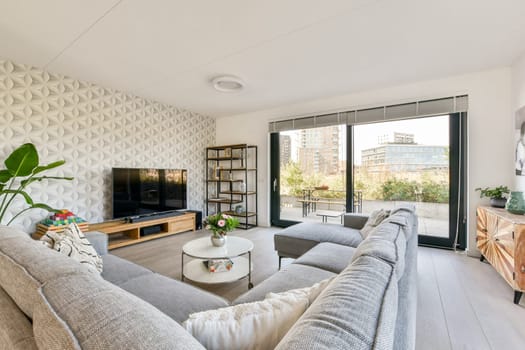 A beautifully designed modern living room featuring contemporary furniture, a geometric wall design, and a bright view from large windows.