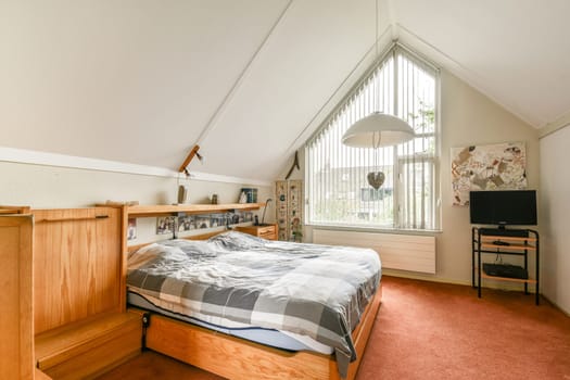 A cozy modern bedroom featuring a wooden bed frame, striped bedding, and large windows letting in natural light, creating a warm and inviting atmosphere.