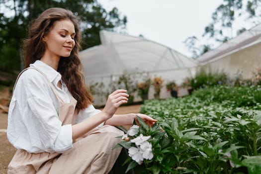 Woman enjoying her time in a greenhouse, dressed in a casual light outfit, surrounded by vibrant flowers, representing themes of gardening, joy, and nature appreciation