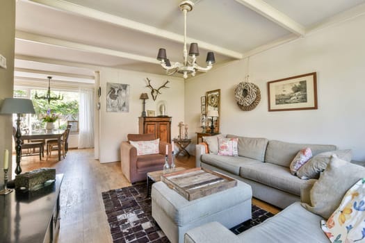 A beautifully designed living room featuring a comfortable sofa, stylish decor, and a dining area that welcomes natural light and warmth into the space.