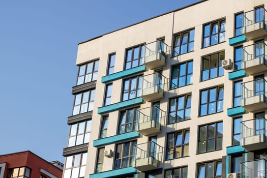 A multistory building that features a substantial number of windows and balconies, providing both light and outdoor space for residents